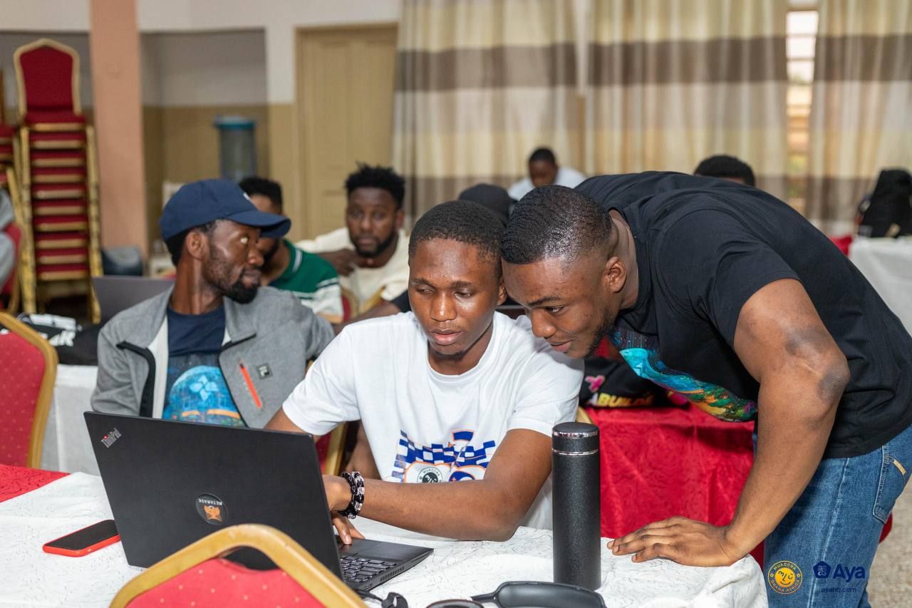 Samuel Dahunsi collaborating with builders around a laptop during ODHack at muAccra